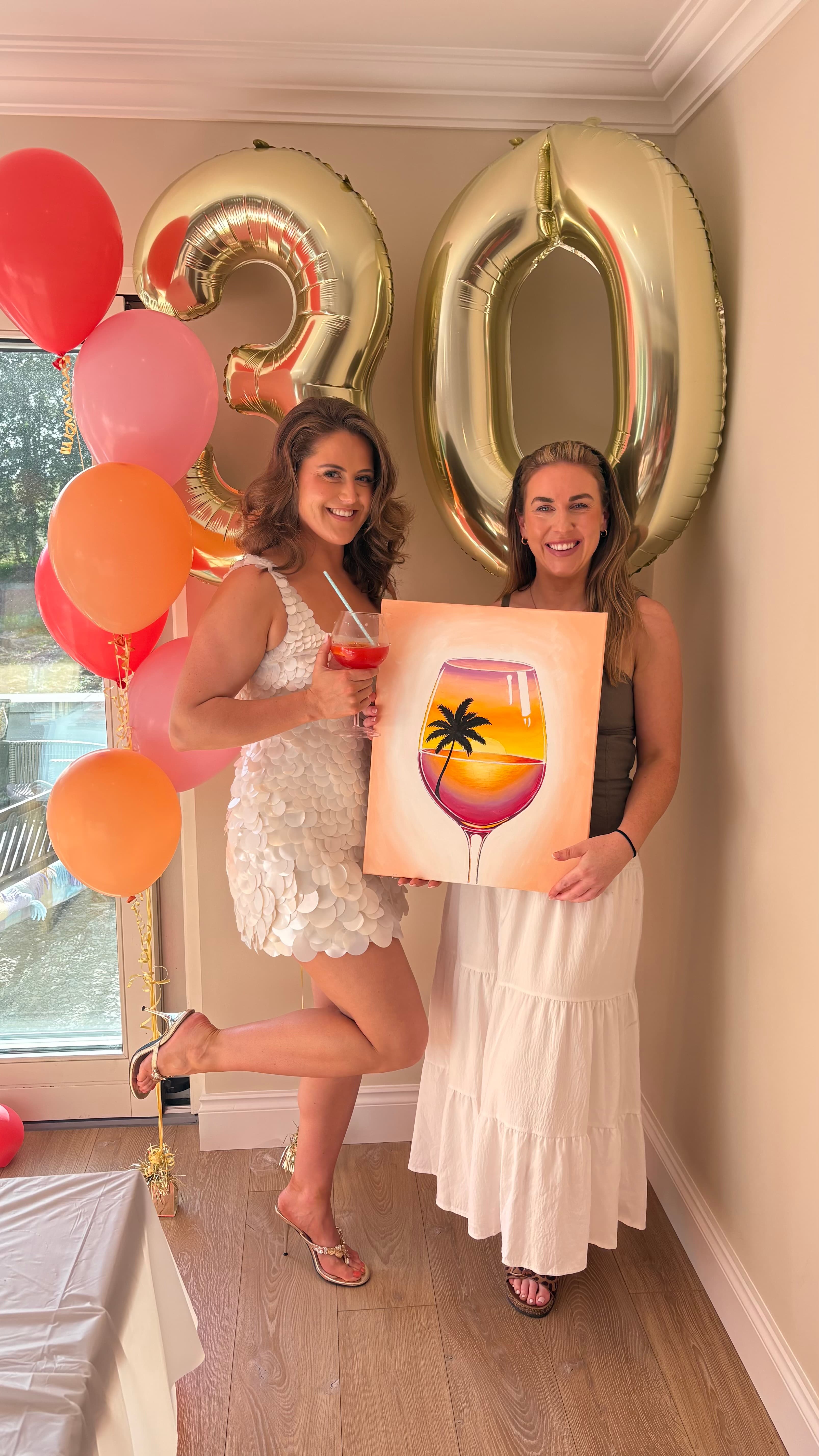 Two women at a 30th birthday sip and paint with wine glass painting