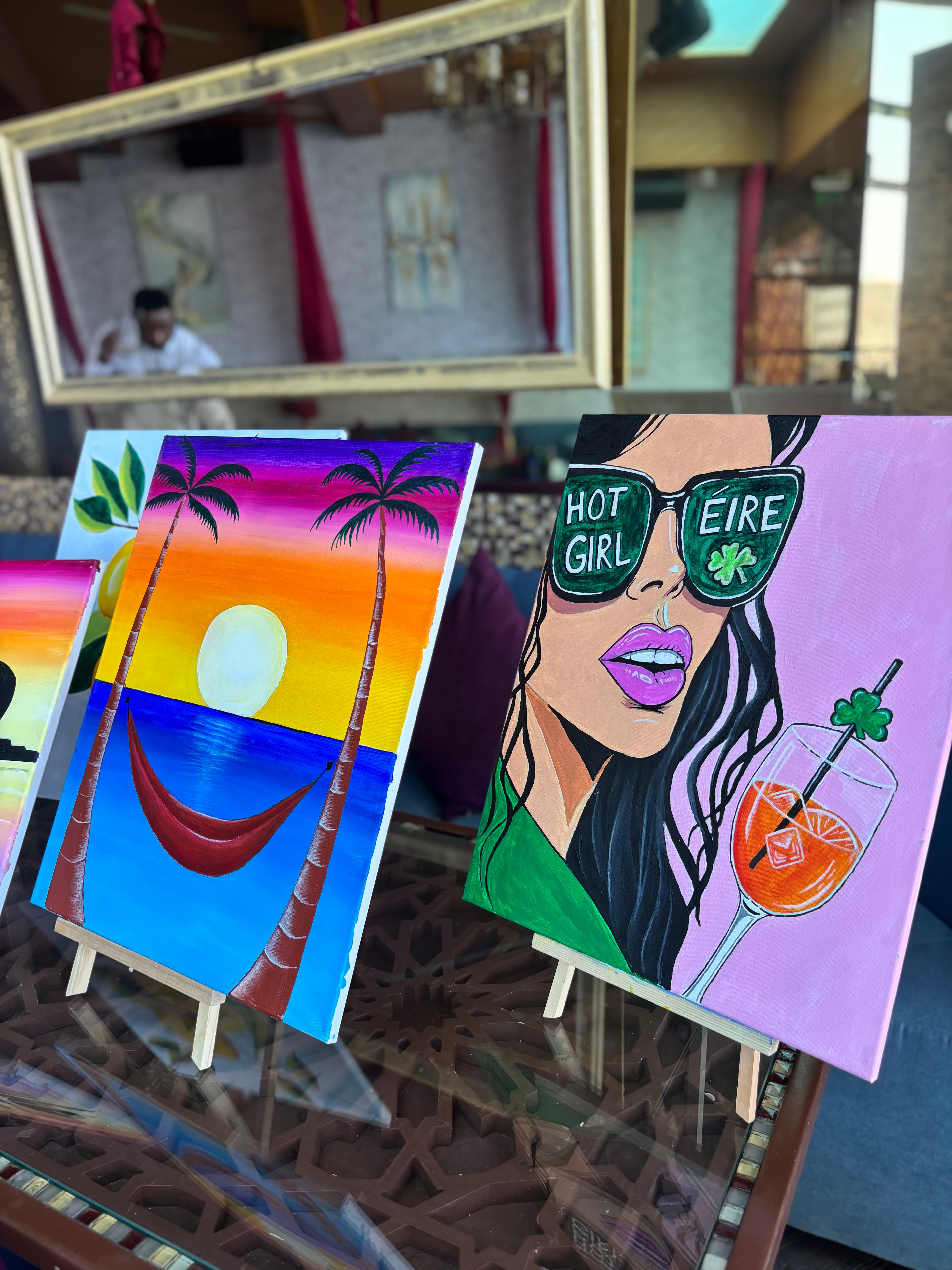 Tropical sunset and Hot Girl Éire paintings on easels